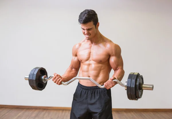 Рубашки мускулистый мужчина, поднимая штангу в тренажерный зал — стоковое фото
