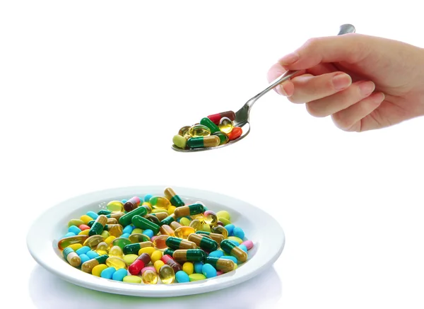 Красочные капсулы и таблетки на тарелка с ложкой в руке, закрыть вверх — стоковое фото