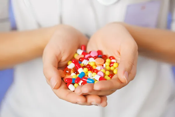 Таблетки, таблетки и препараты кучи в руке врача на синий backgroun — стоковое фото