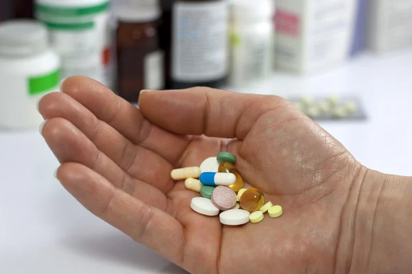 Таблетки в руку против лекарства в аптеке — стоковое фото